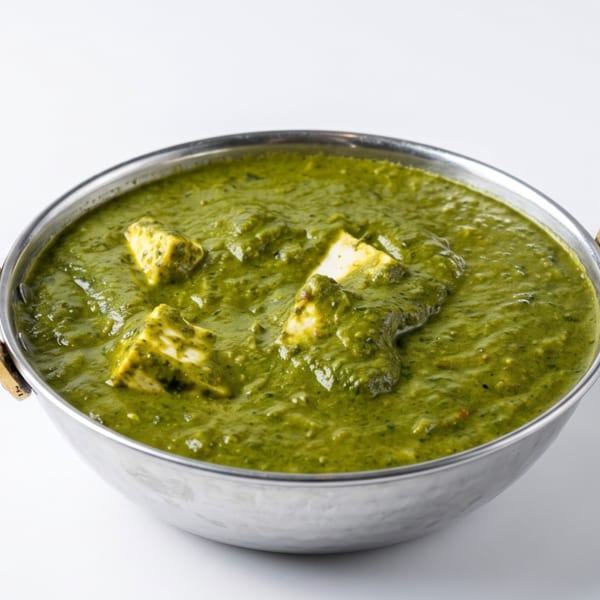Palak Paneer, a vibrant green spinach and cheese curry, served in a traditional silver karahi.